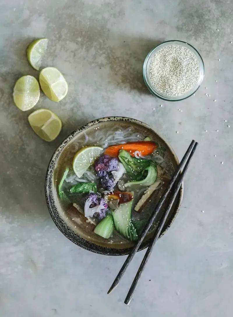 Bol de soupe asiatique aux légumes, citron vert et baguettes